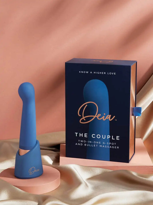 The Couple - Deia - Blue silicone dual-motor vibrator with ergonomic curves next to navy Deia packaging on peach fabric, ouiboutique. - 2 moteurs ou +, anal, clitoridien, point g, prostate, vibrateur