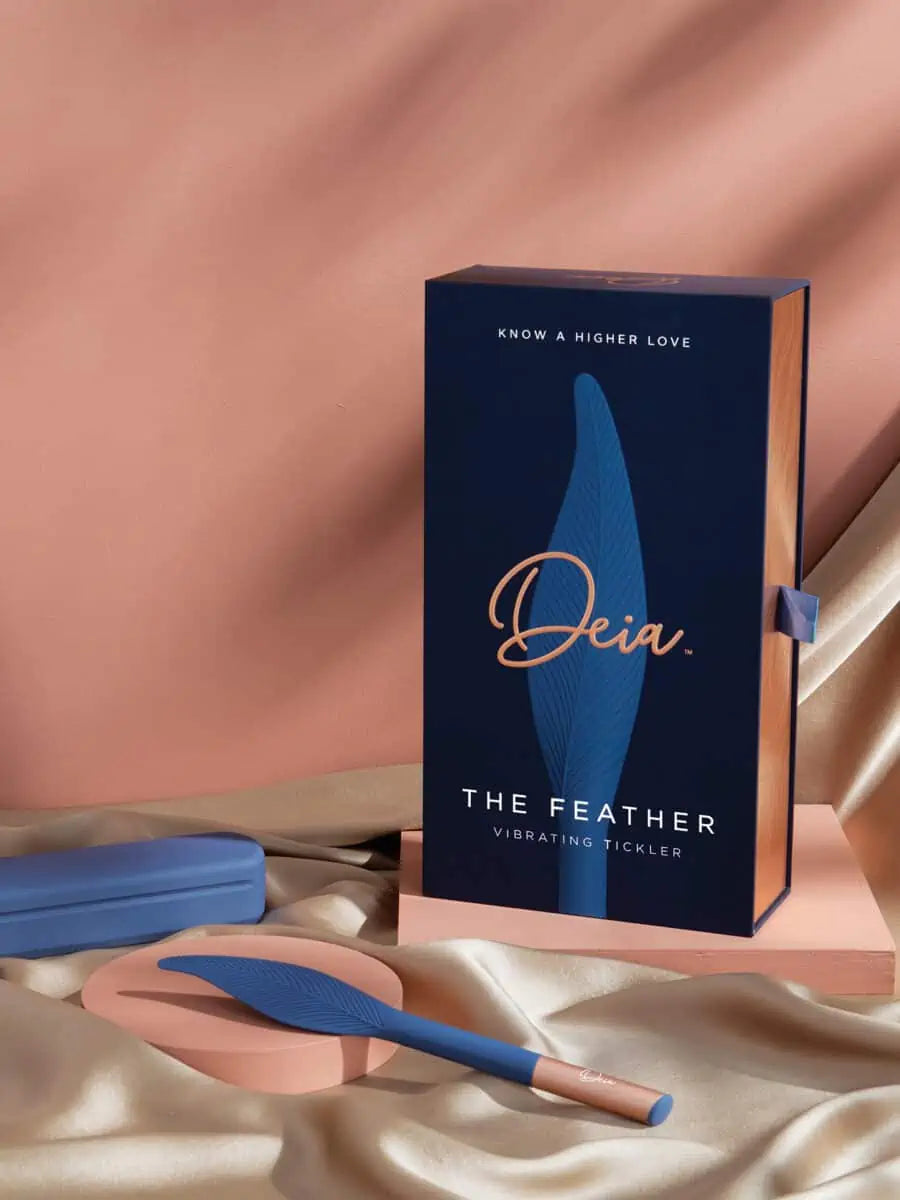 The Feather - Deia - Slim navy blue clitoral vibrator with sleek silver base held by hand ouiboutique. - clitoridien, couple, perinée, vibrateur