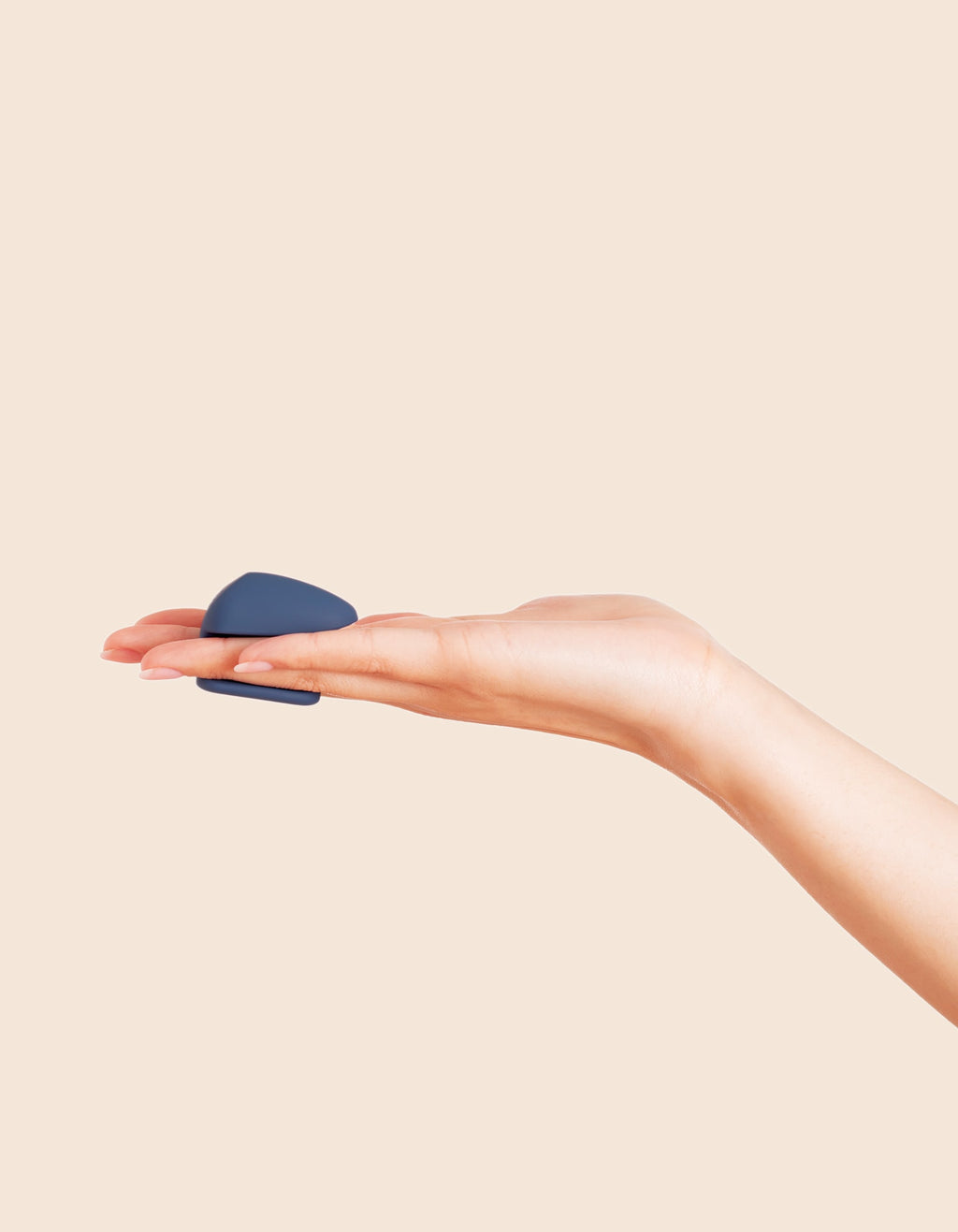 The Wearable - Compact navy blue wearable device held between hands with transparent tip, ouiboutique style.