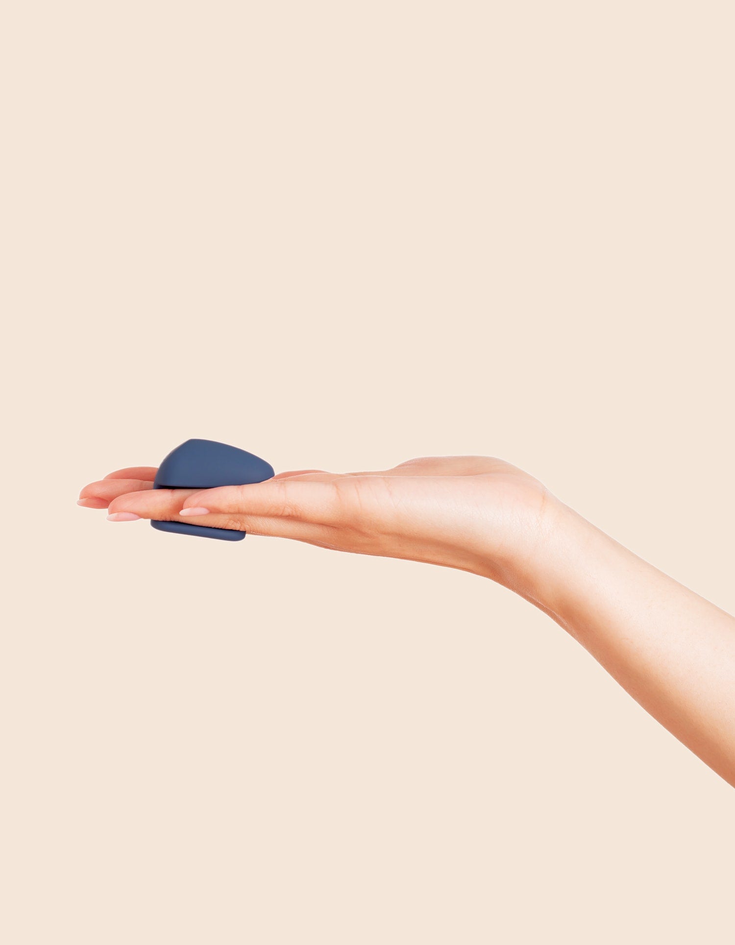 The Wearable - Compact navy blue wearable device held between hands with transparent tip, ouiboutique style.