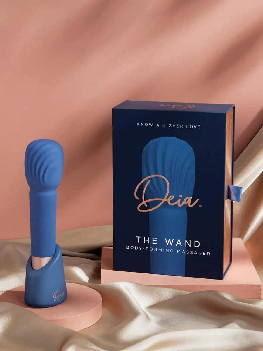 The Wand - Deia - Blue textured wand vibrator standing on a blue base next to navy Deia branded box with gold lettering ouiboutique. - clitoridien, couple, massage, vibrateur