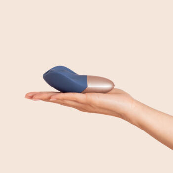 The Arouser - Jouet à pulsations - Compact blue and rose gold clitoral pulsation vibrator resting on an open hand, ouiboutique. - clitoridien, vibrateur