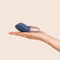The Arouser - Jouet à pulsations - Compact blue and rose gold clitoral pulsation vibrator resting on an open hand, ouiboutique. - clitoridien, vibrateur