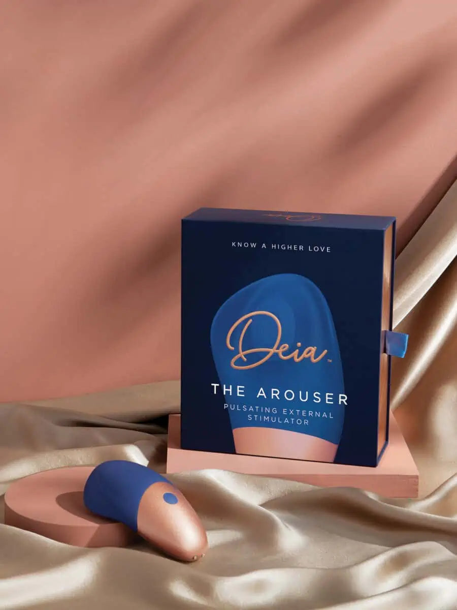 The Arouser - Jouet à pulsations - Compact blue and rose gold clitoral pulsation vibrator resting on an open hand, ouiboutique. - clitoridien, vibrateur